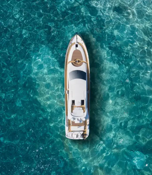 A huge white super Mega yacht on blue water in Italy. White sport yacht near the coast on the sea aerial view. Superyacht on clear water near the rocks, top view.